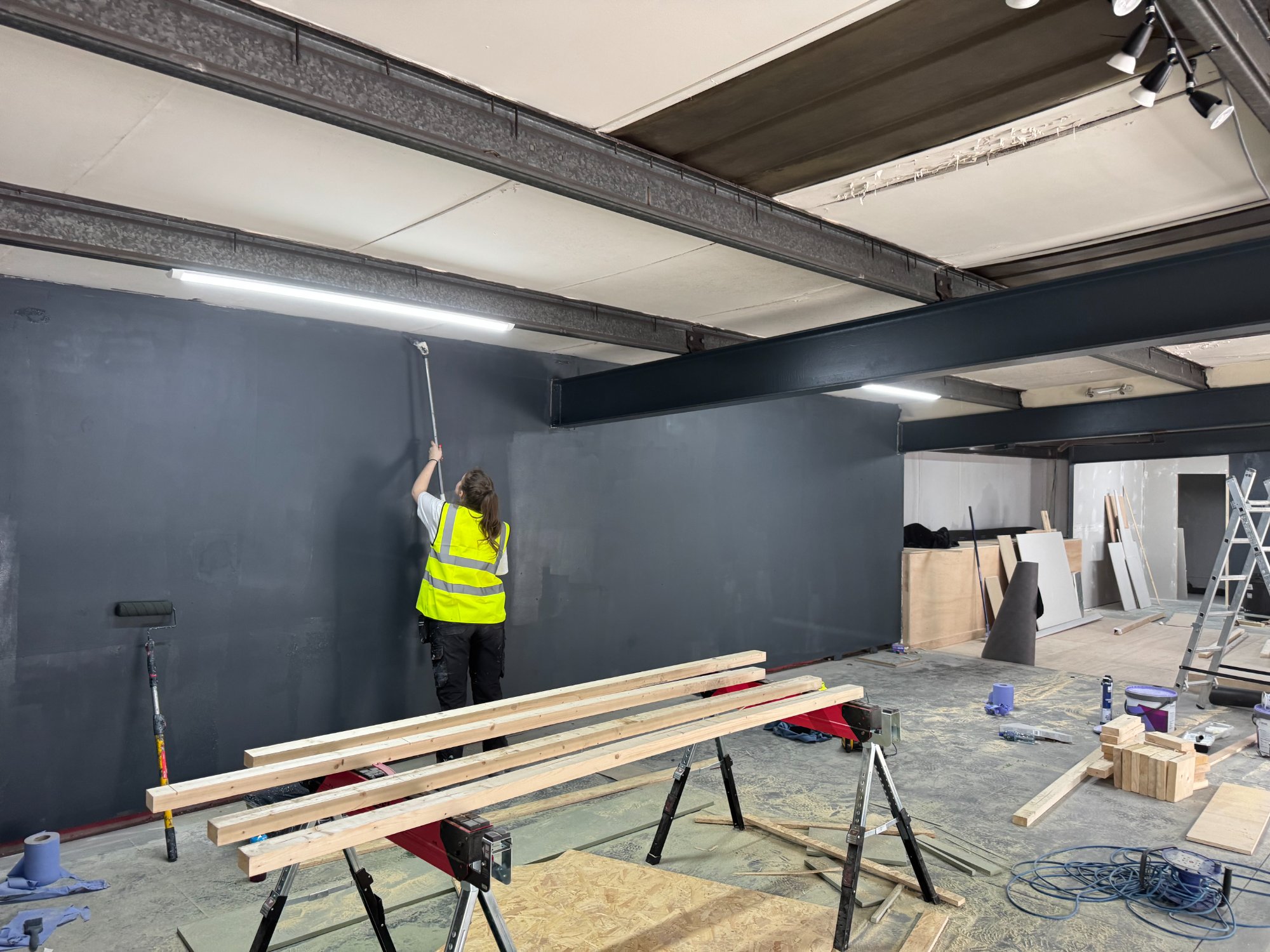 Volunteer painting the large dark wall