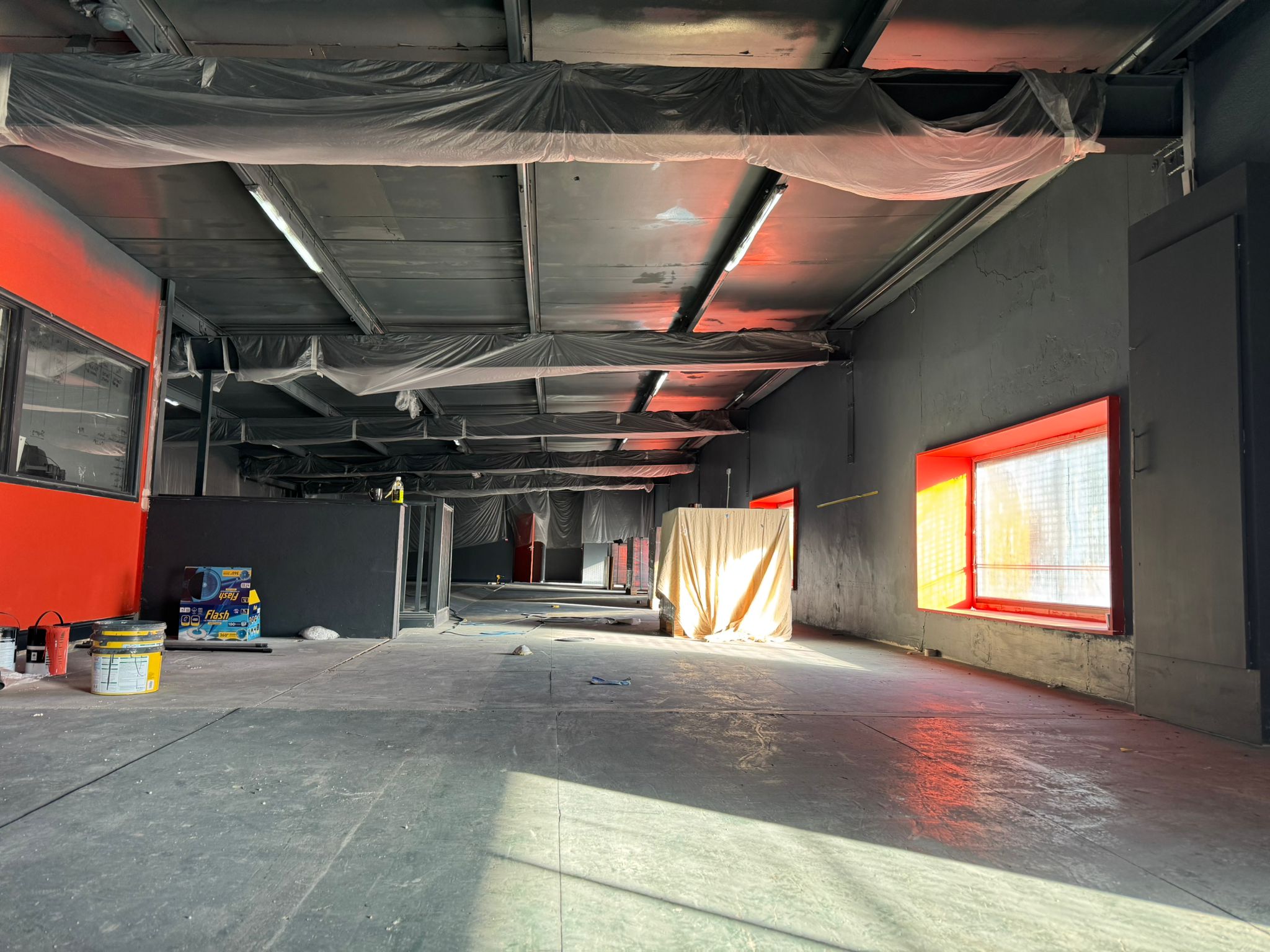Gym floor before flooring laid, paint pots and protection sheeting